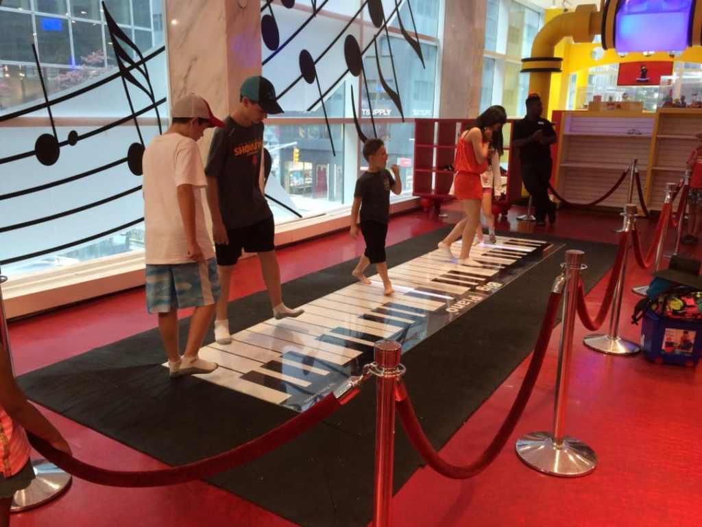 Kids playing on a large floor piano.