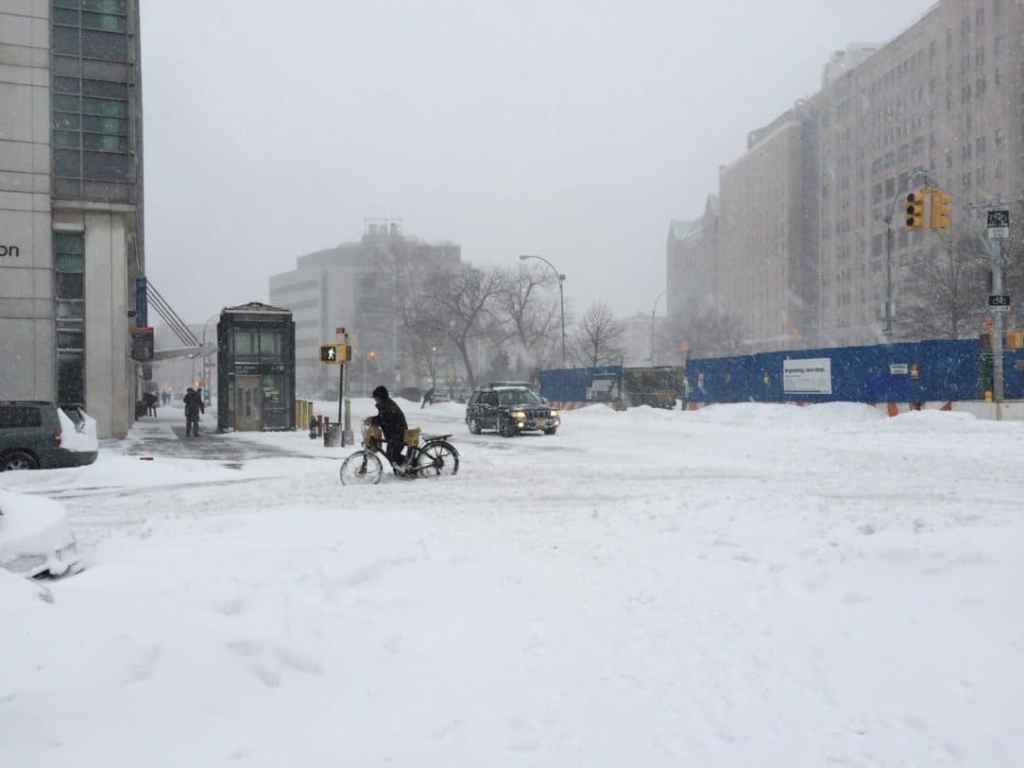 Delivery man pushing his bicycle through the snow.