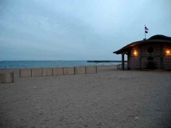 A pier stretching out into the ocean from Coney Island's boardwalk area.